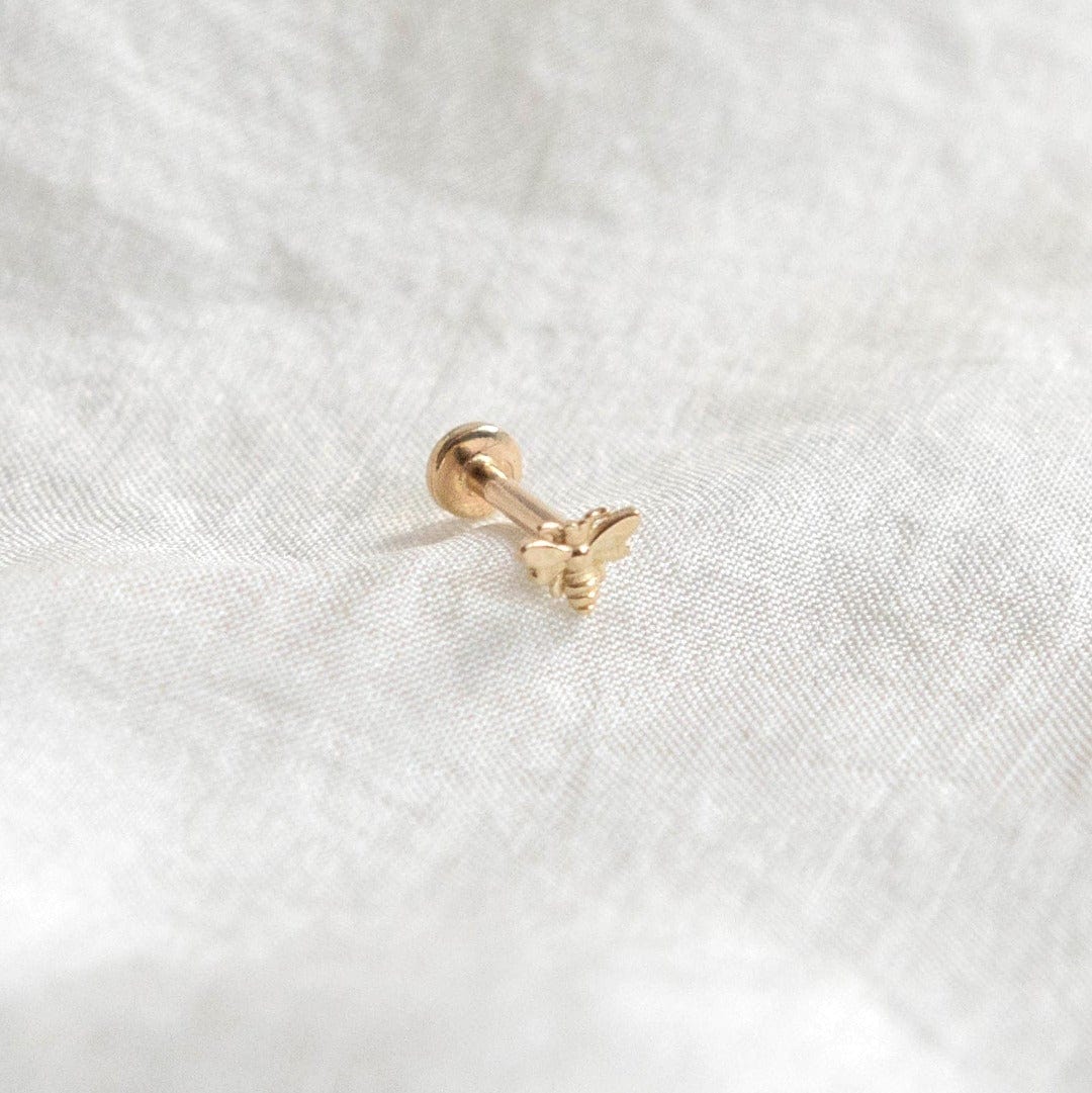14 Carat Yellow Gold Tiny Bee Labret Piercing shown on silk background