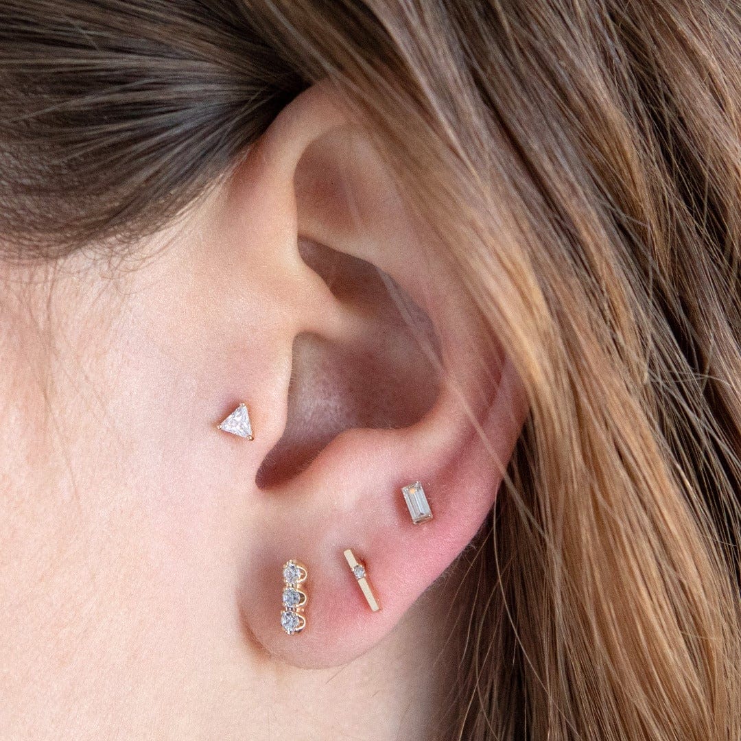 14 Carat gold facet labret shown in the tragus position on an ear model with 3 addition sold gold lobe piercing 