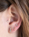 14 Carat gold facet labret shown in the tragus position on an ear model with 3 addition sold gold lobe piercing 
