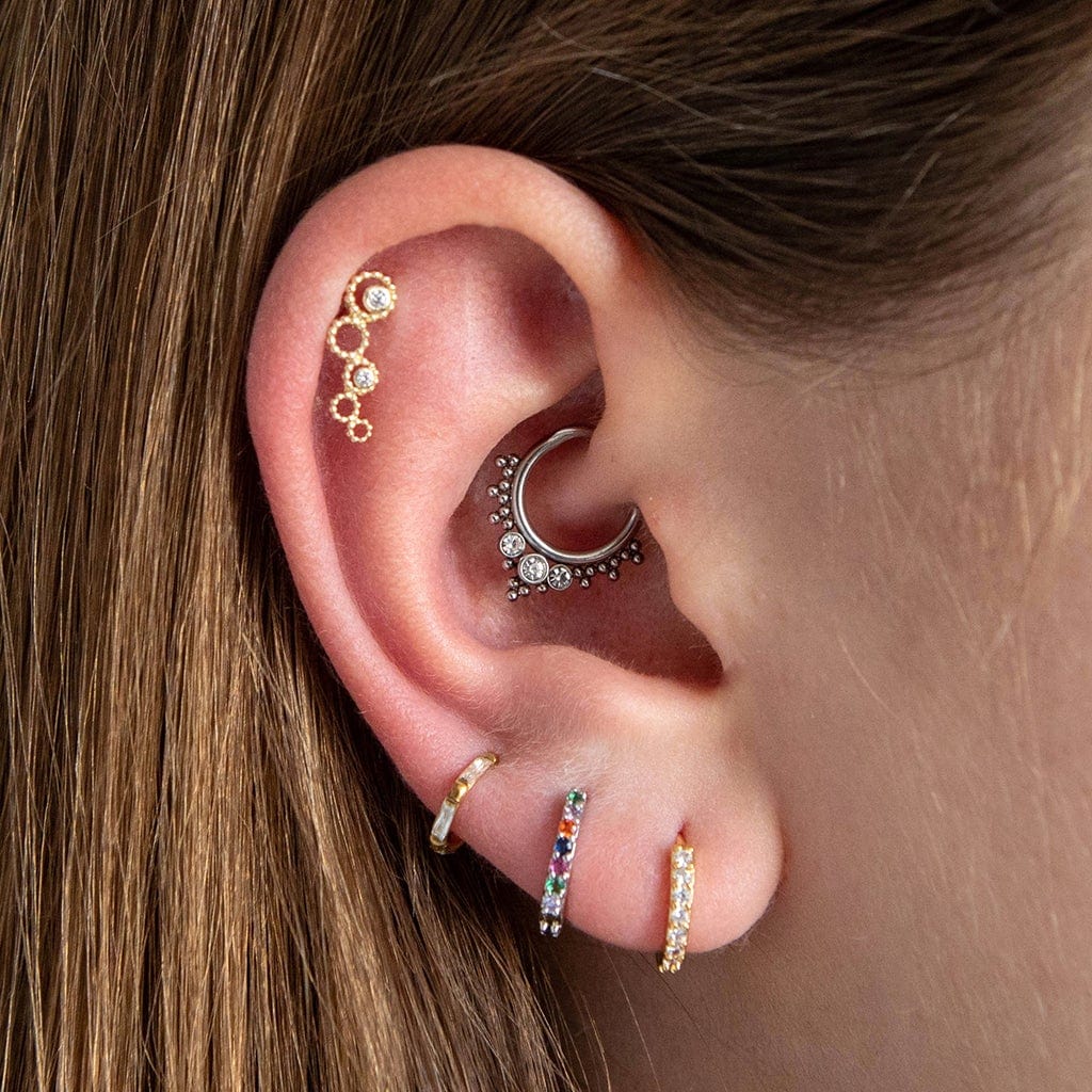 14 Carat Solid Gold Hoops Barbell Earring with 2 tiny circular cut clear CZ gems shown in the helix position of the models ear. The model also wears a daith hoop and 3 hoop earrings in the lobe.