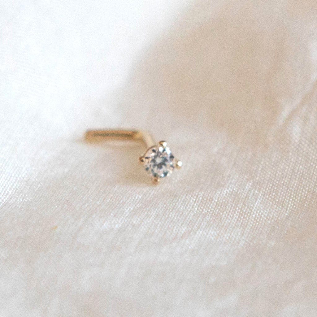 14 Carat Gold Solitaire Nose Stud with 1 single tiny clear CZ gems on silk background