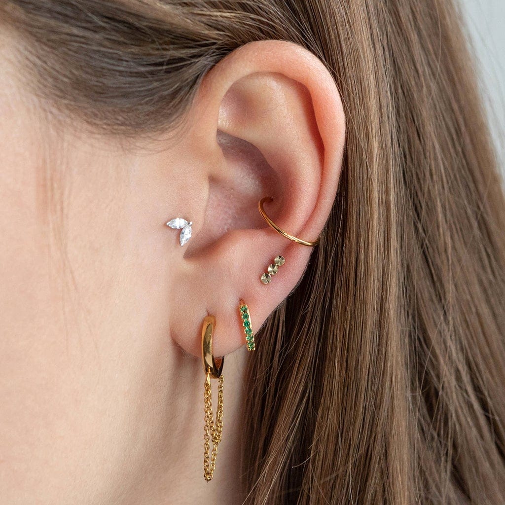 14 Carat solid gold leaf piercing with 2 clear cubics zirconia crystals with threaded labret back shown in the tragus position on the model with hoop clicker hoop and 3 lobe piercings in gold