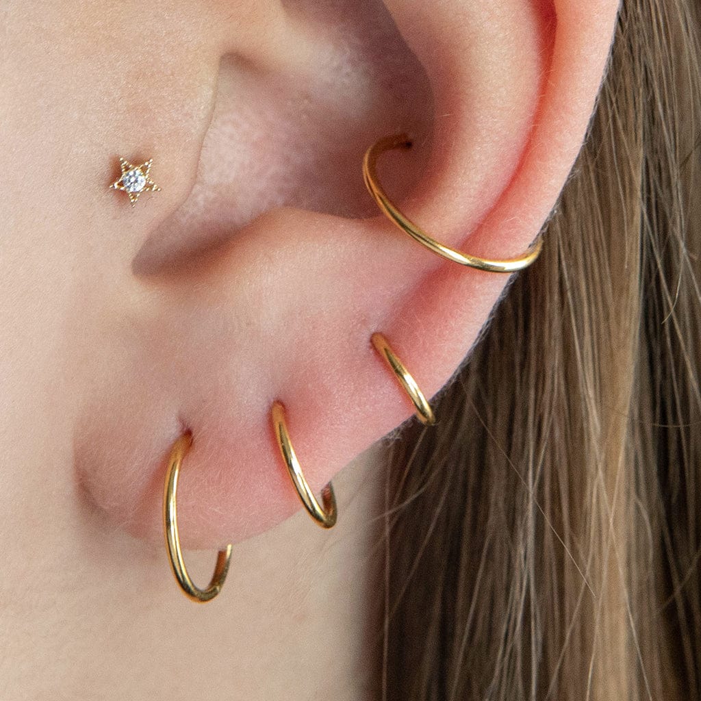 Classic 18 gauge segment rings, shown on the model in 3 lobe positions and inner conch in gold. The model also wears a tiny CZ star in her tragus position